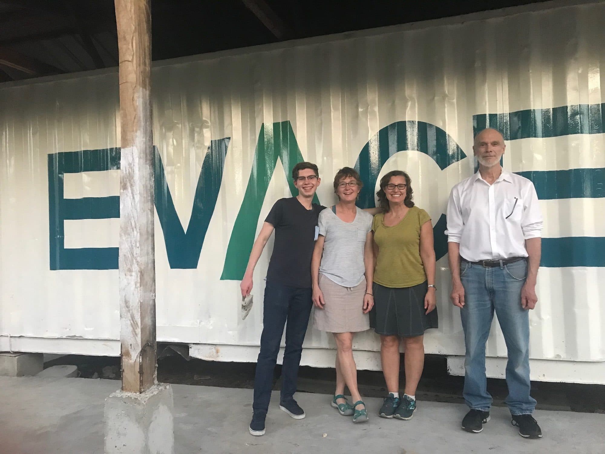 Four EVACE board members standing in front of the shipping container painted with the EVACE name