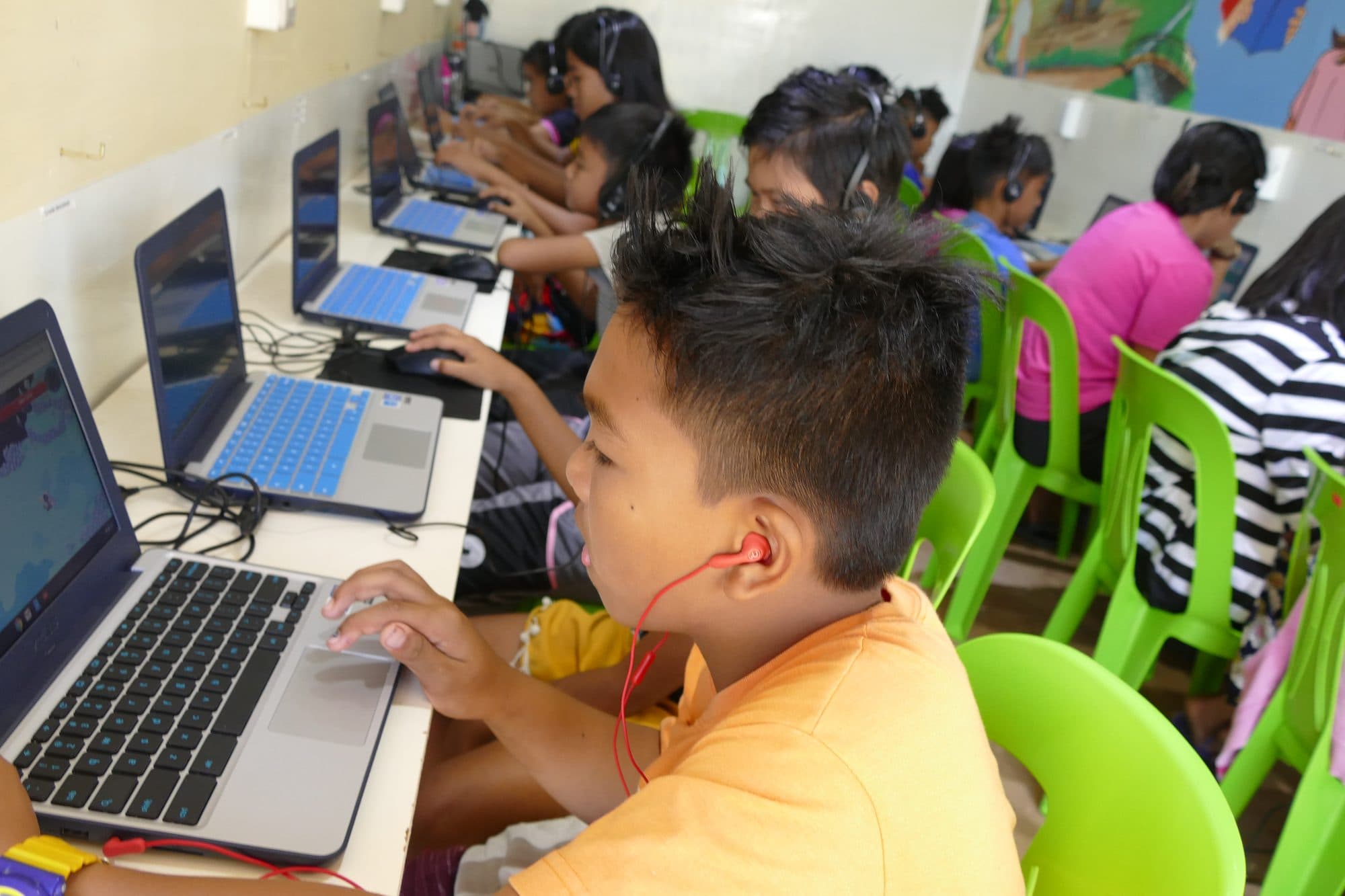 A boy with earphones works at a laptop