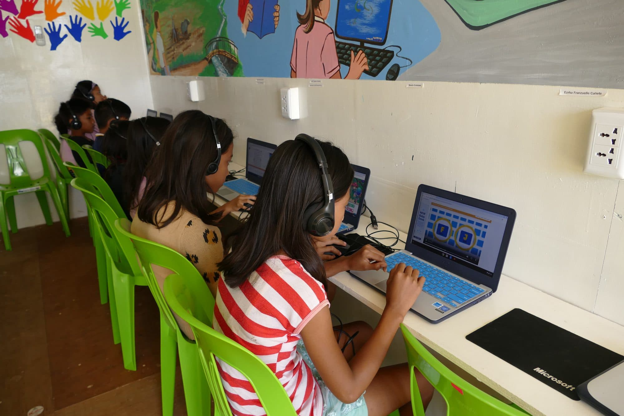 Students with headphones on work at their laptops
