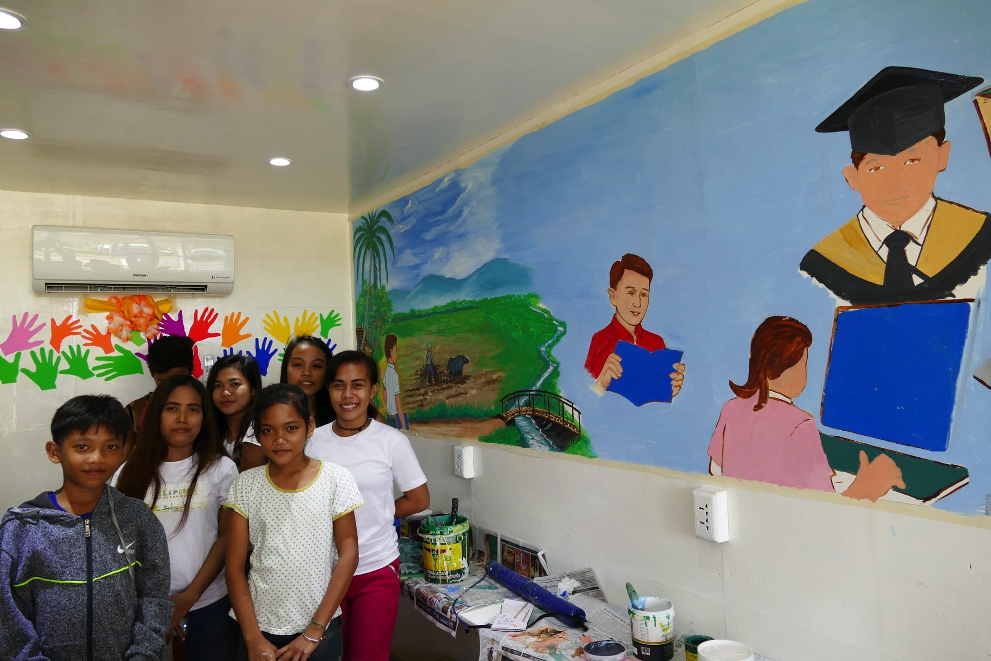 Students standing in front of the mural they painted inside the classroom