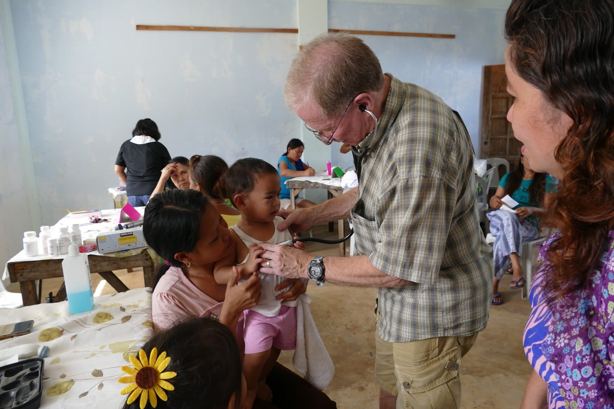 A visiting doctor listens to a child's chest at the clinic