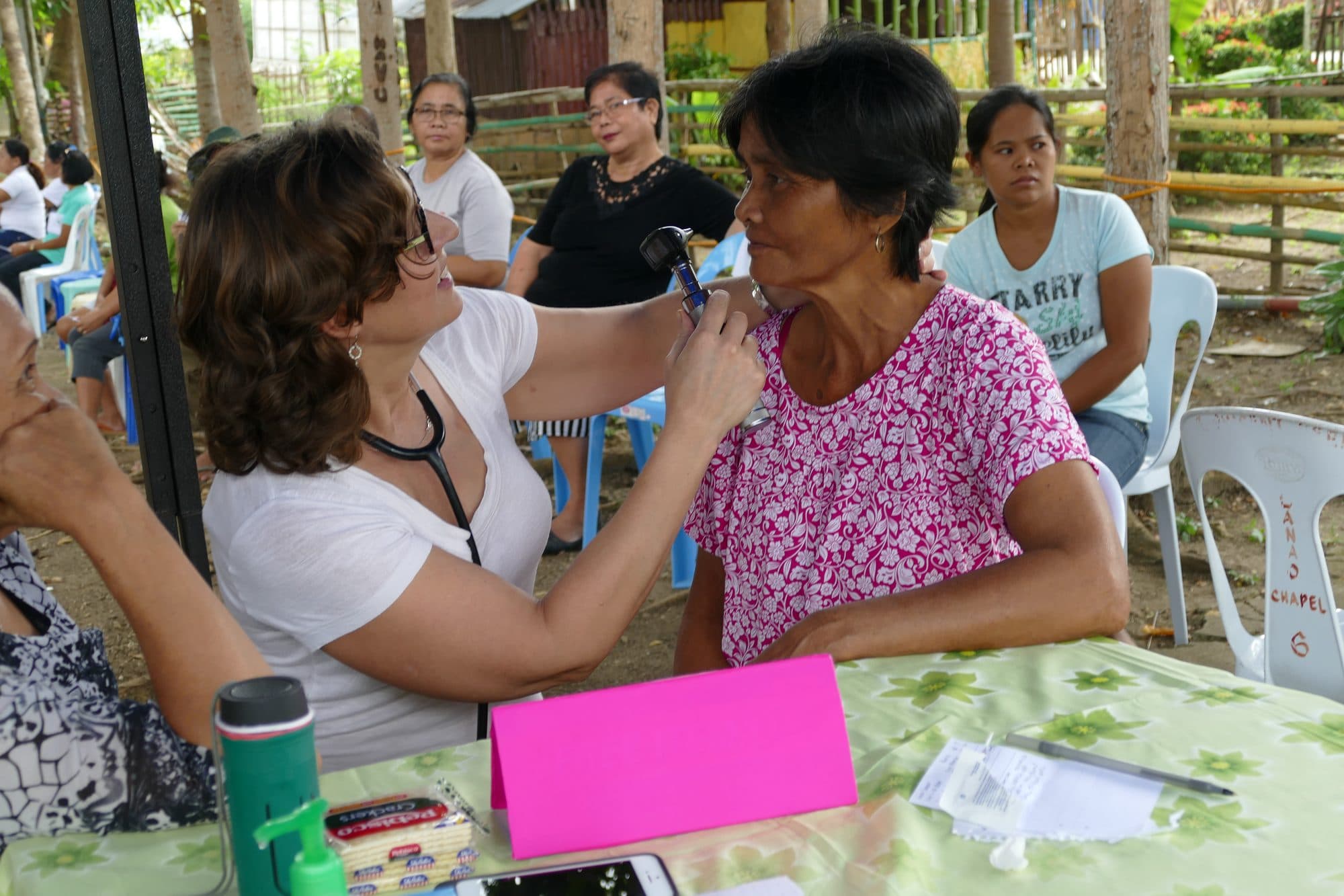 A clinic volunteer checks a woman's ear at a village clinic