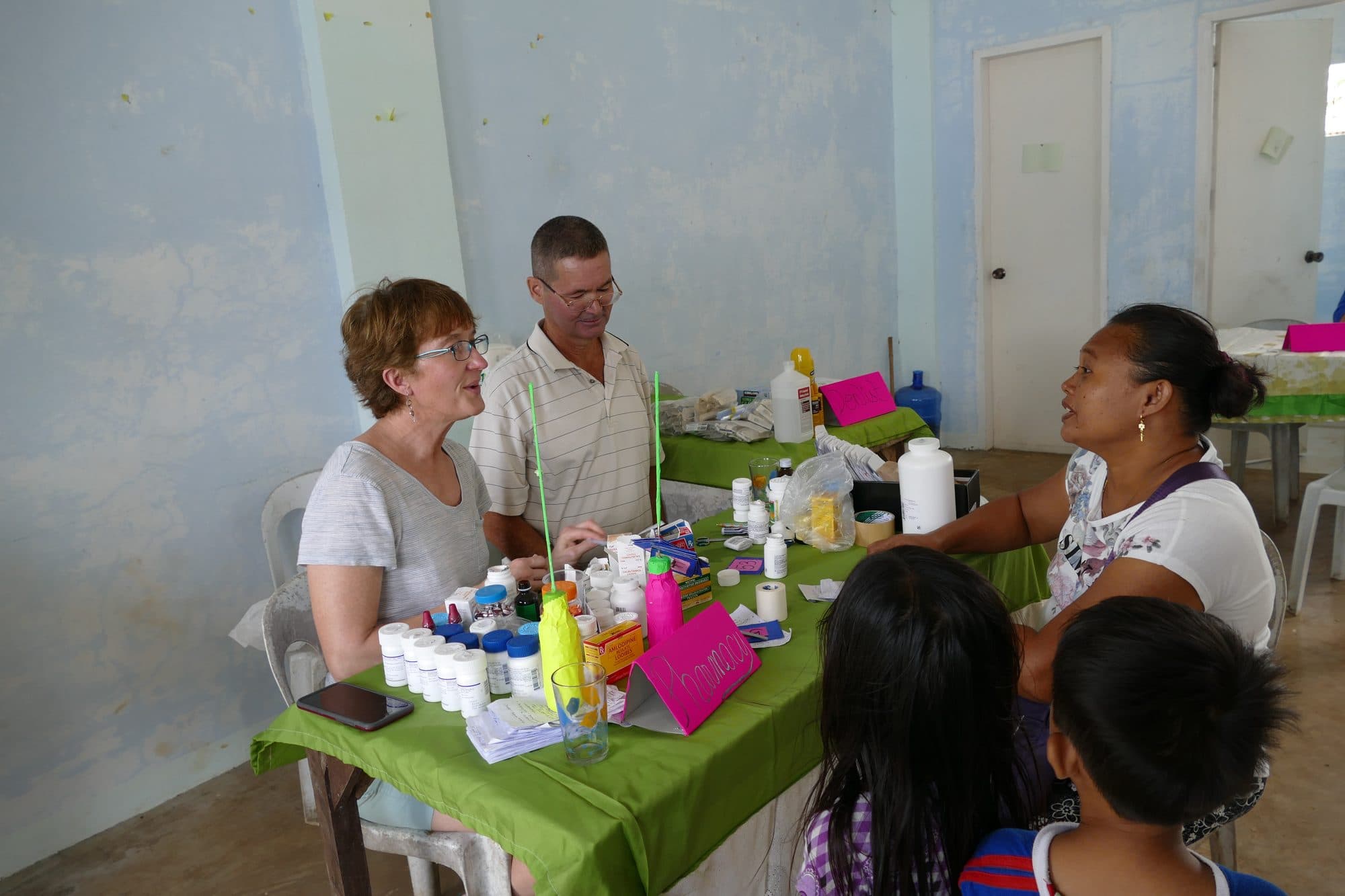 Volunteers hand out medicine at a table of bottles