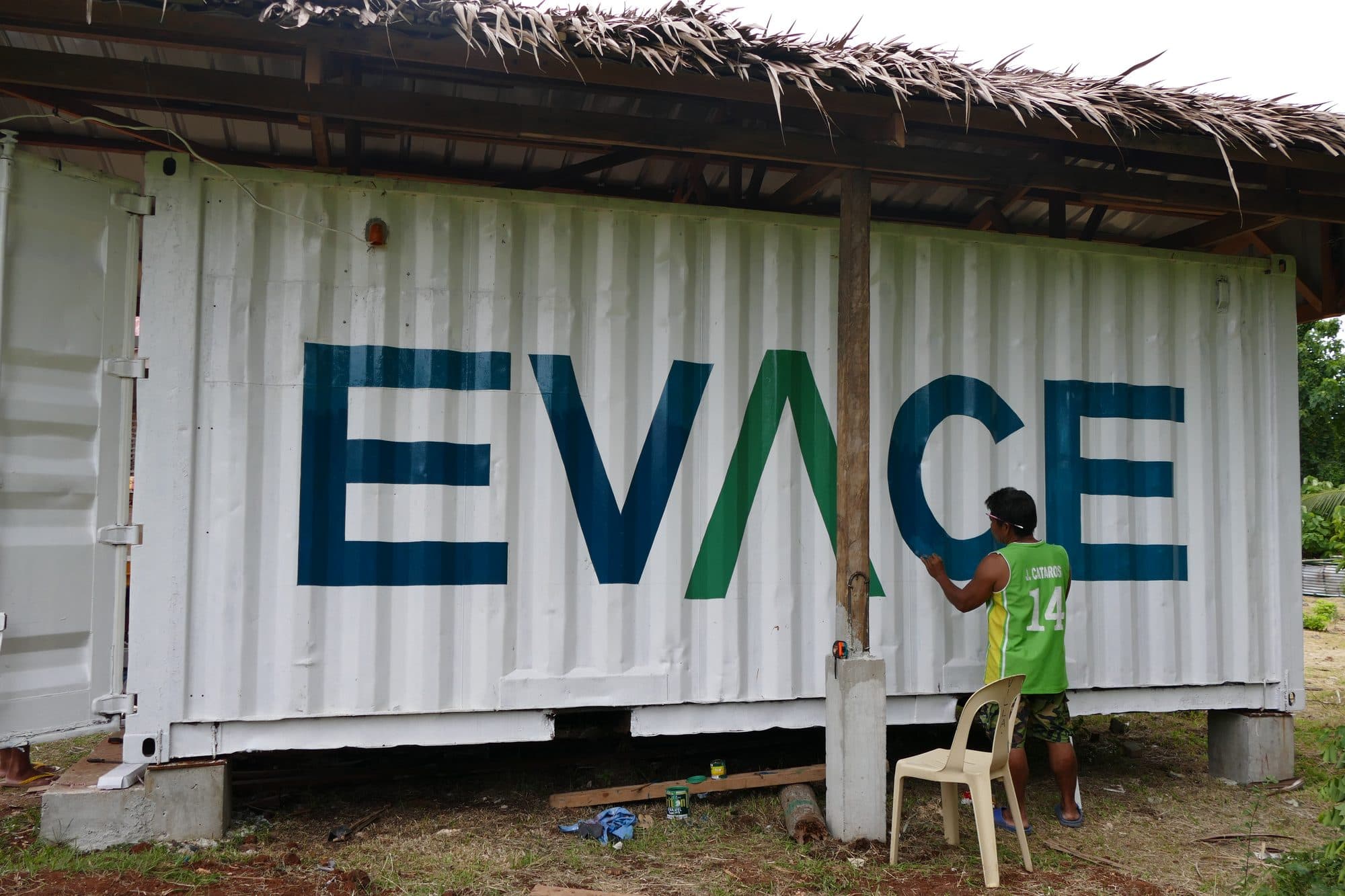 A painter finishing the EVACE name on the side of the container