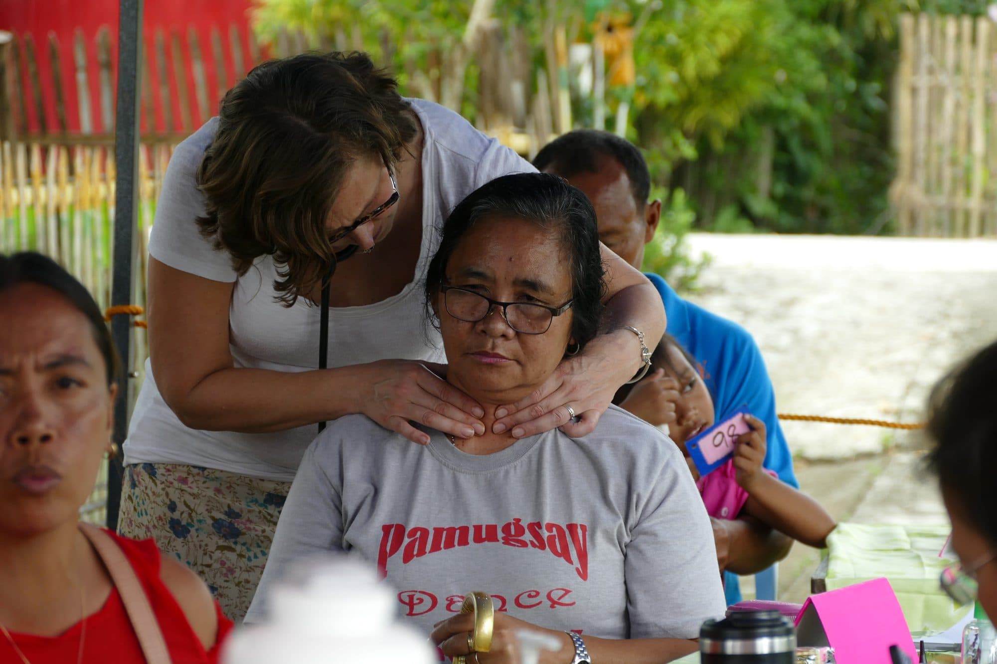 A volunteer checks a woman's neck at a traveling clinic