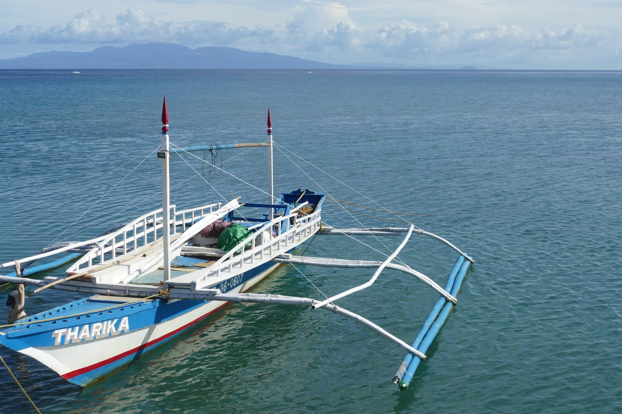 A white outrigger boat in clear blue water