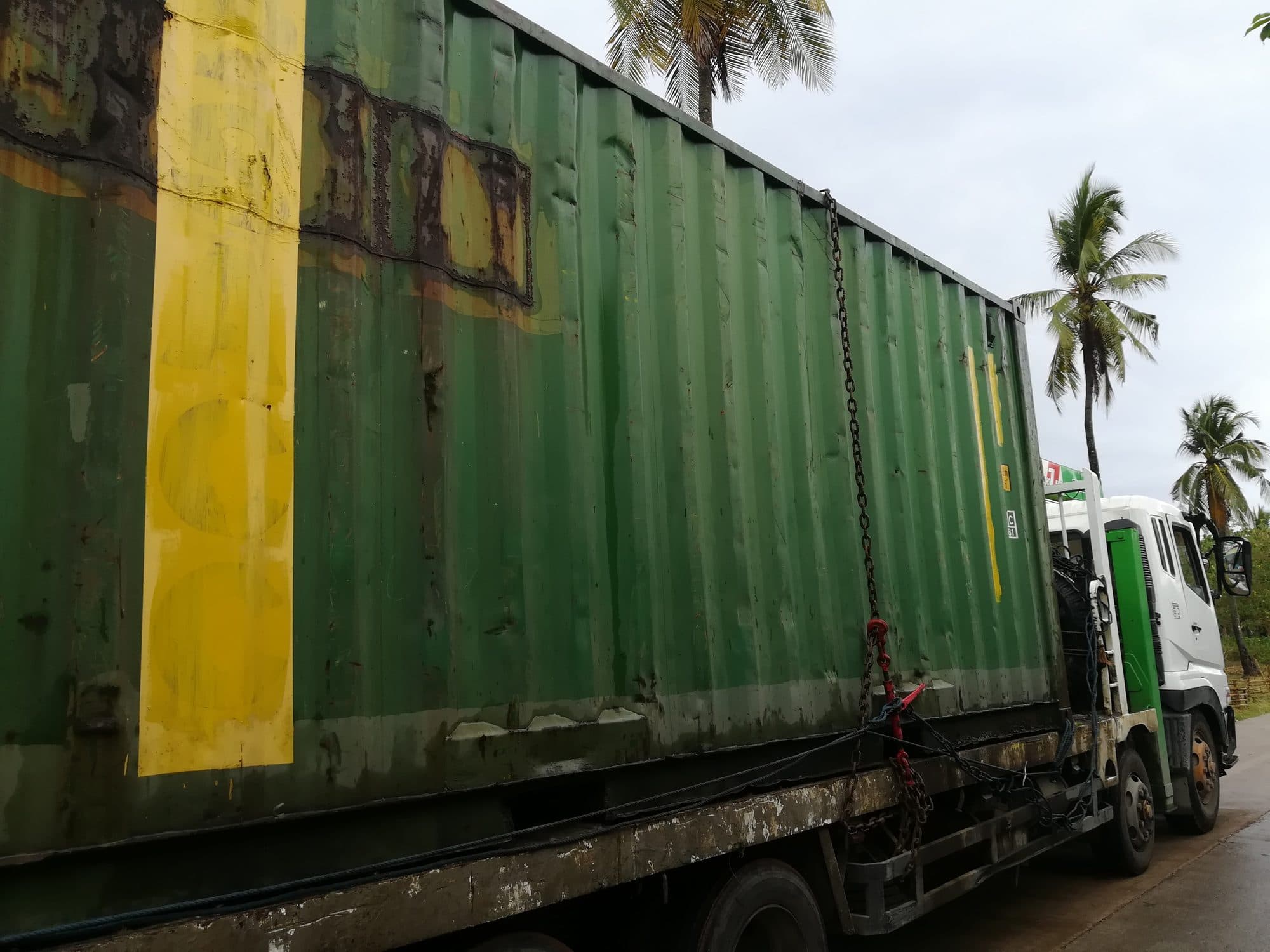 A green shipping container on the back of a truck